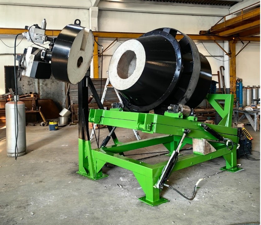 Rotary melting furnace with green hydraulic frame and alumina refractory lining visible at the mouth