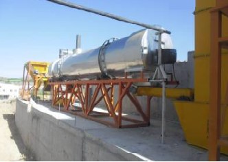 Outdoor rotary dryer on an orange steel frame with feed hopper